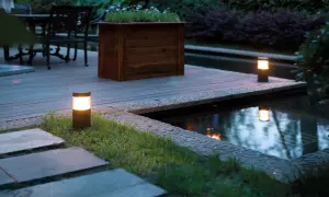 Illuminazione da giardino: lanterne moderne creano un'atmosfera magica lungo il laghetto e il patio in legno.