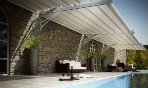 Tettoia addossata moderna su muro in pietra, con divano, sdraio e piscina.