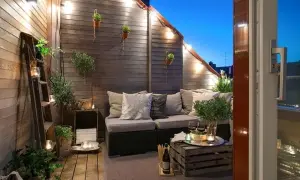 Accogliente terrazza con divanetto, luci soffuse e piante. Idee decorazioni giardino fai da te con scale vintage e cassette di legno.
