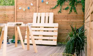 Idee tavoli con pallet: un'area esterna con un tavolo da lavoro improvvisato e un divano fatto di pallet, pronto per essere assemblato.