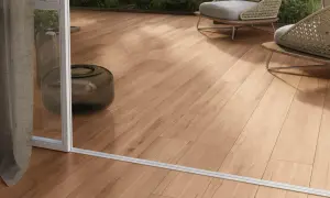 Posa gres effetto legno su un terrazzo moderno con sedie wicker e piante verdi.