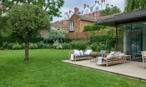 Un'oasi verde perfetta per chi ama progettare giardino. Un prato curato, un patio con mobili in bambù e una vista su edifici storici.