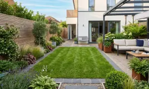 Un moderno giardino con prato verde, arredi da esterno e aiuole curate, che crea piccoli giardini da sogno.