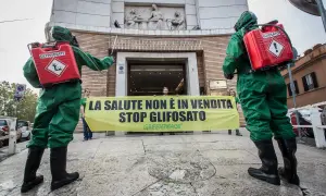 Due persone in tute protettive con bombole di glifosato protestano contro il suo uso, ricordando che il diserbante è pericoloso per l'uomo.