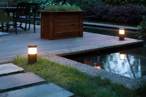 Illuminazione da giardino: lanterne moderne creano un'atmosfera magica lungo il laghetto e il patio in legno.