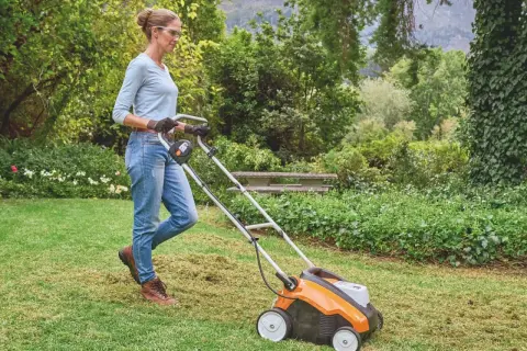 Donna usa un arieggiatore per il prato, rimuovendo feltro e muschio. Un modo efficace per capire come arieggiare il prato e farlo respirare.