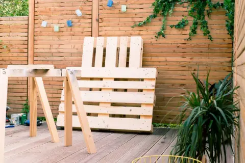 Idee tavoli con pallet: un'area esterna con un tavolo da lavoro improvvisato e un divano fatto di pallet, pronto per essere assemblato.