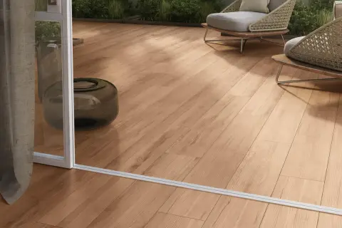 Posa gres effetto legno su un terrazzo moderno con sedie wicker e piante verdi.
