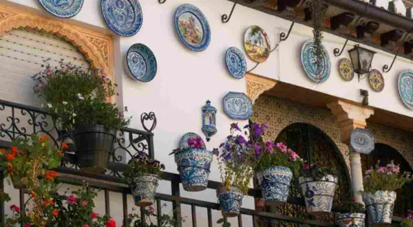 Decorazioni pareti esterne fai da te con piatti decorati e vasi fioriti, un tocco di colore e stile.