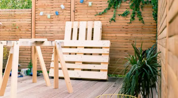 Idee tavoli con pallet: un'area esterna con un tavolo da lavoro improvvisato e un divano fatto di pallet, pronto per essere assemblato.