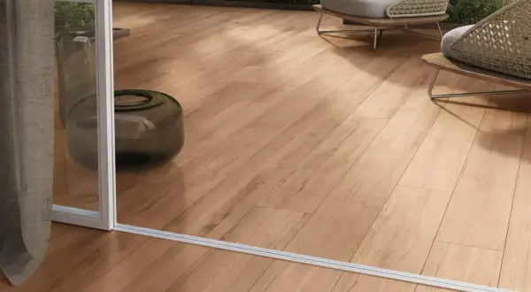 Posa gres effetto legno su un terrazzo moderno con sedie wicker e piante verdi.