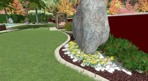 Un grande masso domina un'aiuola con fiori gialli e cespugli rossi. Un'idea per un giardino grande con un tocco naturale.