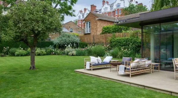 Un'oasi verde perfetta per chi ama progettare giardino. Un prato curato, un patio con mobili in bambù e una vista su edifici storici.