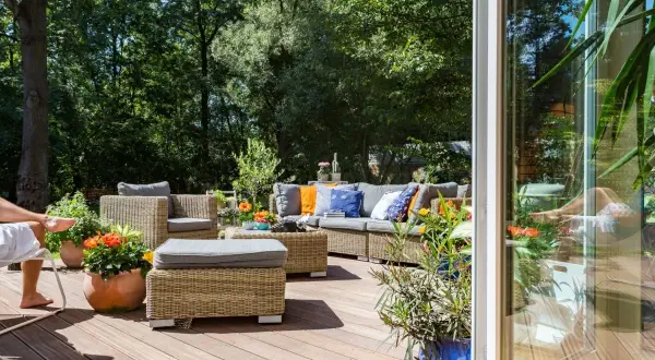 Un'accogliente area relax in rattan con divani e poltrone, perfetta per godersi le **idee spazio esterno casa** in un giardino lussureggiante.