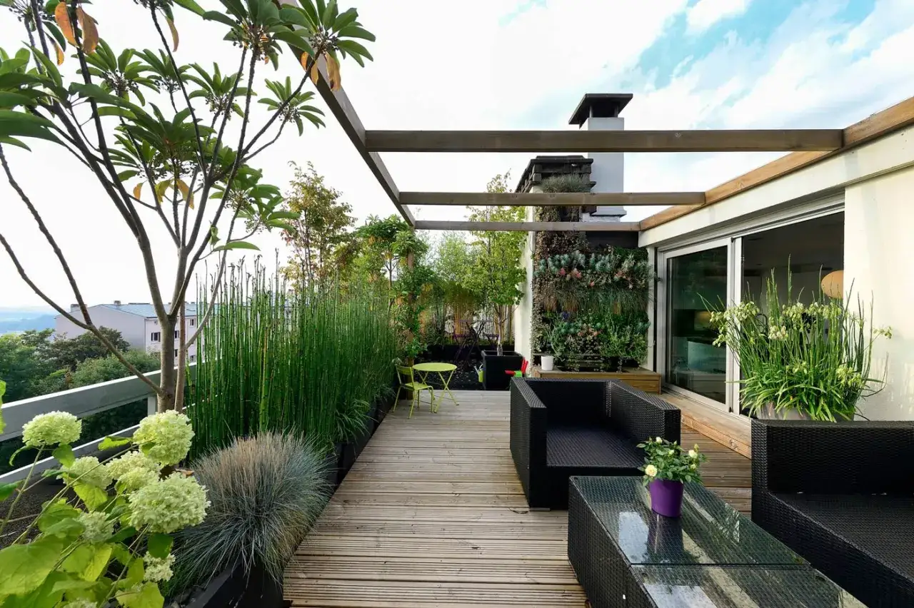 Un terrazzo scoperto arredato con mobili neri, piante verdi e un giardino verticale. Un esempio di come arredare un terrazzo scoperto con stile e funzionalità.