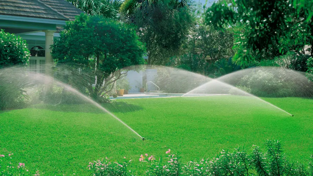 Irrigatori automatici in azione su un prato verde lussureggiante, un esempio di quando innaffiare il prato per mantenerlo sano e rigoglioso.