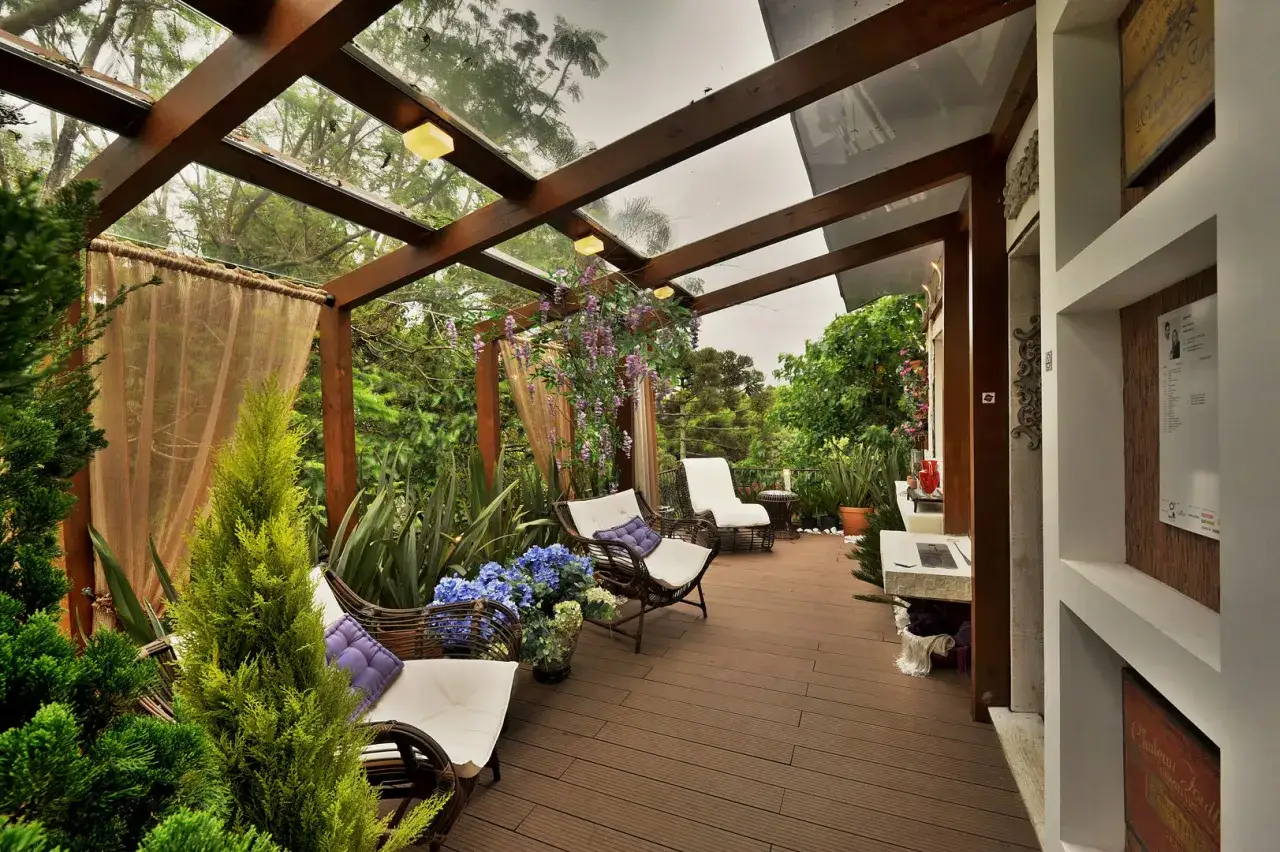Un'oasi verde con sedute comode sotto una tettoia di legno e vetro. Perfetto per idee giardino grande e relax.