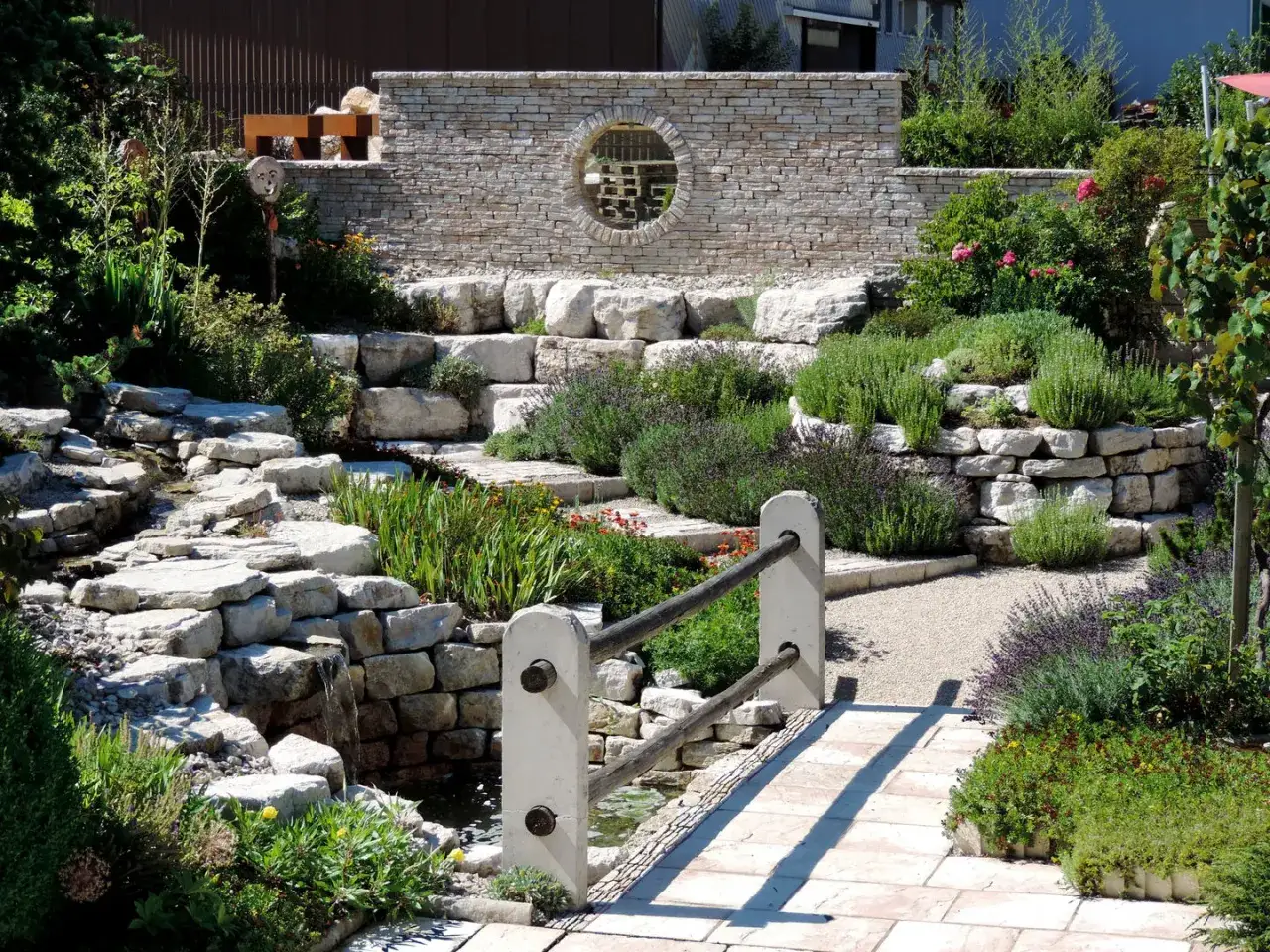 Giardino zen con cascata e muretto in pietra, un esempio di idee muro giardino per creare un angolo di pace.