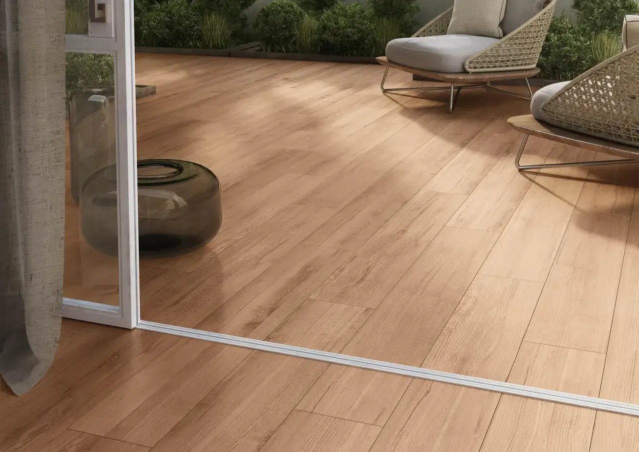 Posa gres effetto legno per un terrazzo accogliente con sedie wicker e piante verdi.