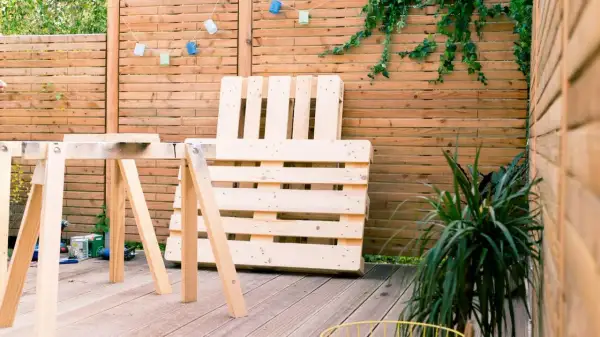 Idee tavoli con pallet: un'area esterna con un tavolo da lavoro improvvisato e un divano fatto di pallet, pronto per essere assemblato.