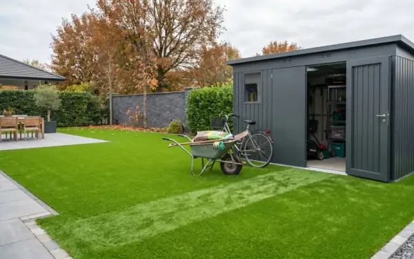 Giardino moderno con prato sintetico impeccabile. Carriola, bici e capanno attrezzi suggeriscono idee per giardini con prato sintetico a bassa manutenzione.