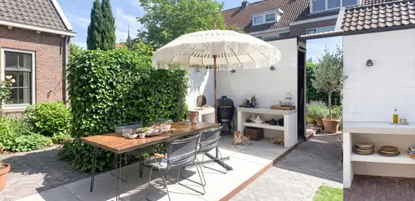 Un'accogliente zona barbecue in giardino con tavolo, sedie, ombrellone e un cane che riposa.