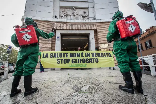 Due persone in tute protettive con bombole di glifosato protestano contro il suo uso, ricordando che il diserbante è pericoloso per l'uomo.